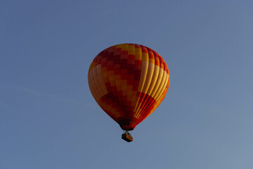 red orange hot air balloon at sunrise flying with mountains line behind minimalist