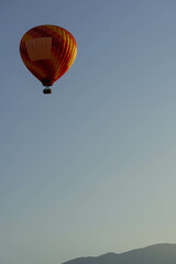 red orange hot air balloon at sunrise flying with mountains line behind minimalist