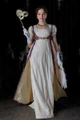 A Regency woman wearing evening attire and holding an ostrich feather fan and a masquerade mask