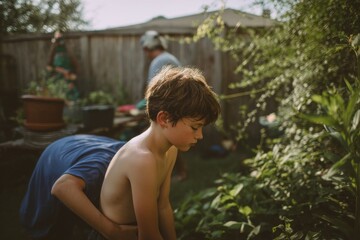 A young boy stands embraced in the garden under the warm summer sun.