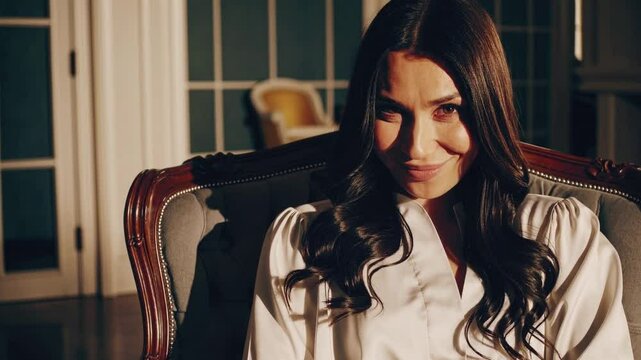 Femme élégante souriant avec malice dans un intérieur raffiné baigné de lumière naturelle

