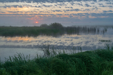 summer sunrise on the river with reflections in the water