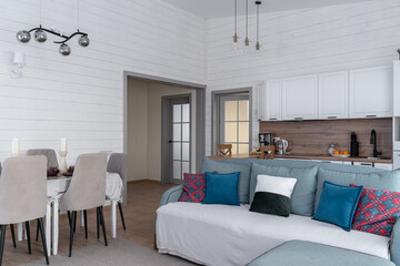 design of kitchen combined with living room in country house. Large sofa with decorative cushions,...
