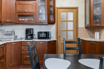 kitchen design in simple style. Built-in kitchen with wooden cabinets. Built-in appliances. Upper...