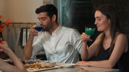 Couple or group friends making toast with cocktail gin tonic, blue hawaii, Cosmopolitan and Grasshopper at dinner table main course, lively conversation celebrating special party nightclub. Vinosity.