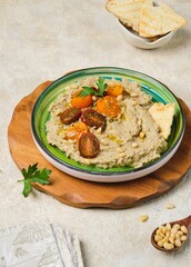 Appetizer, baked eggplant dip with yogurt on a green ceramic plate on a light concrete background....