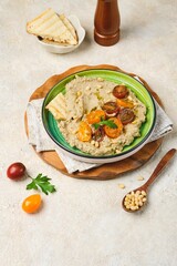 Appetizer, baked eggplant dip with yogurt on a green ceramic plate on a light concrete background. Served with cherry tomatoes, toasted bread and pine nuts. Recipes eggplant.