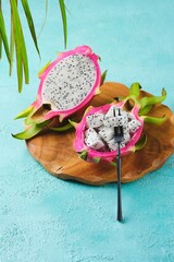 Cubed pitahaya or dragon fruit pulp in a bowl made of its peel on a wooden board on a turquoise...