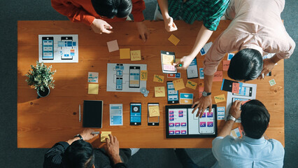 Top down view of business team writing idea on sticky note while planing for Ux Ui design for...