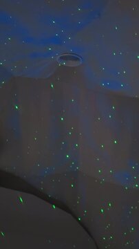 Double bed in glamping house with green lights on ceiling. Nightlight with projector that lights up room with green dots for quiet sleep
