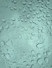 Abstract background photo of rain and water drops and droplets on the sunroof window of a motor vehicle.  
