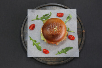 Hamburger in a restaurant on a tray and parchment paper, there are also arugula and tomatoes on the paper