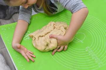 Little chef proudly prepares dough under supervision. Perfect stock photo for baking, education or family lifestyle content.