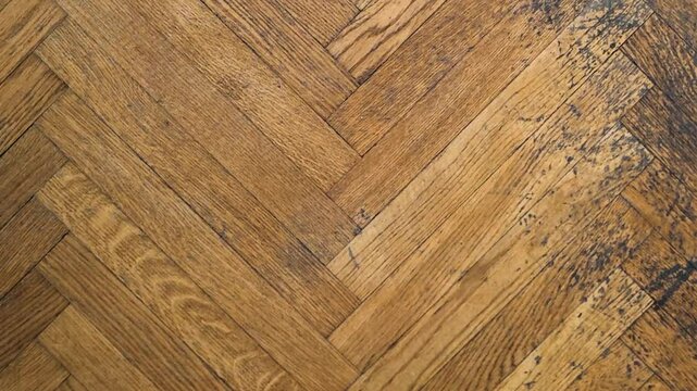 Old parquet flooring with classic herringbone pattern and a dark wooden strip.