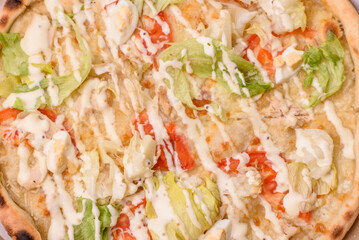 Italian caesar pizza with cheese and chicken, lettuce leaves and sauce