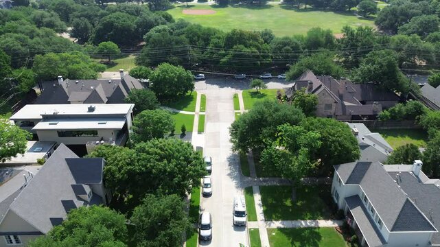 Suburban street toward community park baseball fields in affluent Preston Hollow neighborhood outside Dallas metroplex, expensive mansion houses modern design luxury amenities, mature landscaping