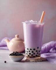 A refreshing and colorful taro bubble tea, in a transparent cup, with a straw, ice, and tapioca pearls. There is a tea pot, tapioca pearls, and a purple cloth near the cup