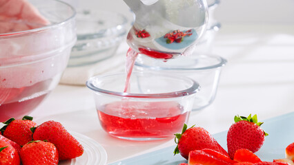 Pouring strawberry jelly into individual serving bowls.