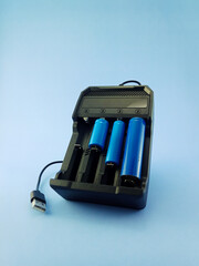 blue rechargeable batteries with charger on light blue background