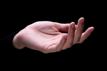 Close-up image of beautiful female hands with delicate pink manicure on nails on black background. Hand skin care, manicure and beauty treatments. Elegant and graceful hands with thin graceful fingers