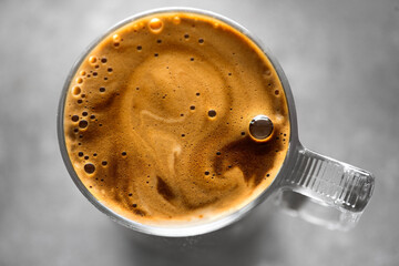 Coffee cup from above, Espresso foam texture, creamy coffee, rich, freshly brewed cup of hot latte. Top view of cappuccino milk foam closeup. Creamy coffee macro shot, on a grey table, top view 