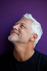 Obraz premium Creative of style for aging men. A studio shot capturing the essence of a modern man. Purple solid background. Trendy men's classic long sweep haircut - midlife white man with white hair.