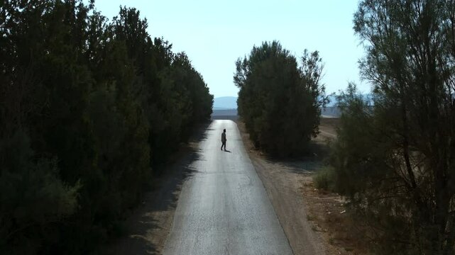 Aerial: Drone Lockdown Shot Of Man Exploring Road In Field On Sunny Day - Tel Arad, Israel