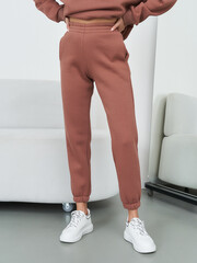 Casual fashion with brown joggers and white sneakers, hands on hips. A stylish and relaxed look,...