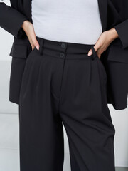 Stylish woman poses confidently in a chic black outfit in a modern studio setting