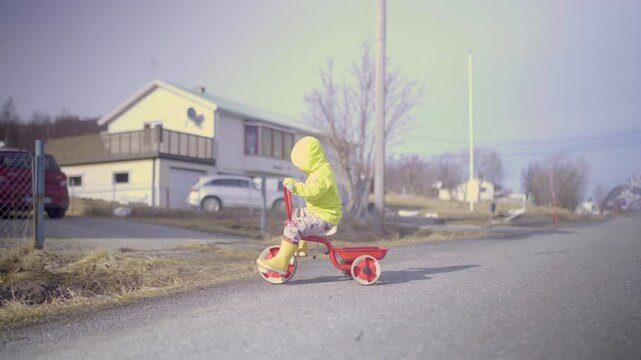 Toddler Boy Learning To Ride Tricycle In Middle Of Road Amidst Houses - Tromso, Norway