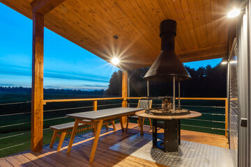 A wooden deck features comfortable seating and a central fireplace, perfect for evening gatherings....