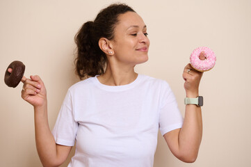 Smiling Woman Holding a Pink-Iced and Chocolate Doughnut in a Playful Pose, Highlighting Choices...