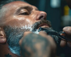 Naklejka premium Close-up of a man getting his beard shaved. The focus is on the detail of the shaving process and the texture of the beard.