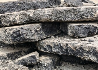 Stacked rough stone blocks with dark textures and contrast in construction site