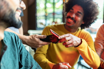 Young African American man paying for drinks with contactless technology in bar, enjoying time with friends.
