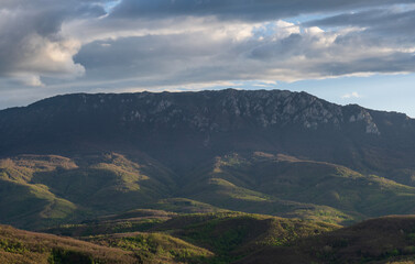 Fototapeta premium View of the Suva Planina mountain range. Open landscape photography. The sun shines on a huge mountain rock on top of the mountain. Mountain peaks in the woods landscape. Photo nature. 