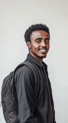 Obraz premium Smiling young Ethiopian man with a black backpack and dark shirt, symbolizing confidence and academic aspirations.