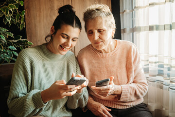 Senior woman and her granddaughter use cellphone to send text messages sms	
