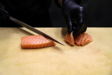 chef experto en sushi cortando con cuchillo grande especial salmón para elaborar sushi y maki © planeta11