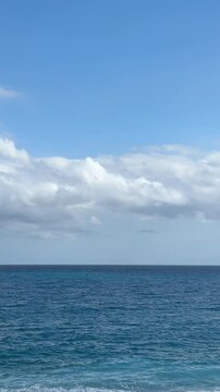Calm ocean waves gently rolling under a bright blue sky with fluffy clouds. Perfect loopable background video for meditation, wellness, or travel 