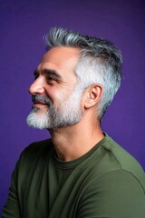 Fototapeta premium A cheerful man radiating warmth and positivity. Trendy men's punk haircut - midlife middle eastern man with middle hair. Purple solid background. Creative of style for aging men.