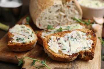 Tasty bread with garlic, herbs and oil on wooden table, closeup