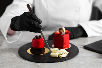 Obraz premium Confectioner decorating tasty dessert at light grey table in kitchen, closeup