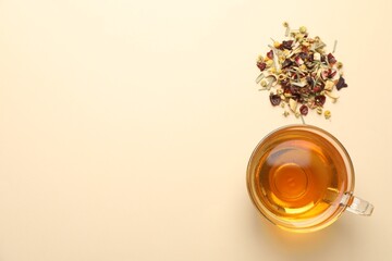 Delicious herbal tea in glass cup and dry leaves on beige background, flat lay. Space for text © New Africa