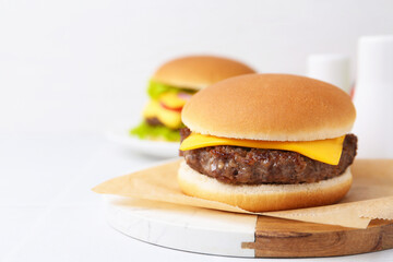 Tasty cheeseburger on white table, closeup. Space for text