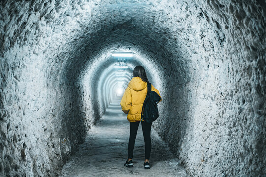 Girl with a backpack is walking on old salt mine tunnel. Salina Turda salt mine, Turda city in Romania. Popular tourist destination