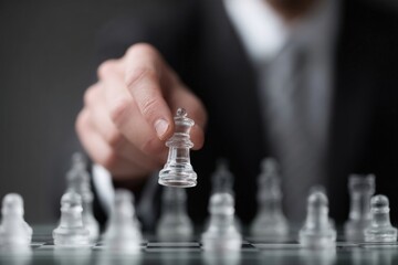 Executive placing transparent chess piece on large chess board