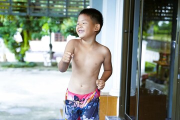 A shirtless boy shows off his slight muscles and dances to music, enjoying a summer day.