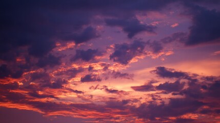Obraz premium Vibrant orange and purple clouds illuminated by sunset light in a tranquil sky, with a soft blurred background creating a dreamy atmosphere that highlights the vivid colors natural beauty of the scene