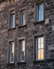 Fototapeta premium 柔らかな夕日が照らす石造り住宅の壁面、控えめに輝く正方形窓